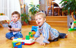 Photo: two cute baby boys playing with toys at home two cute baby boys playing with toys at home