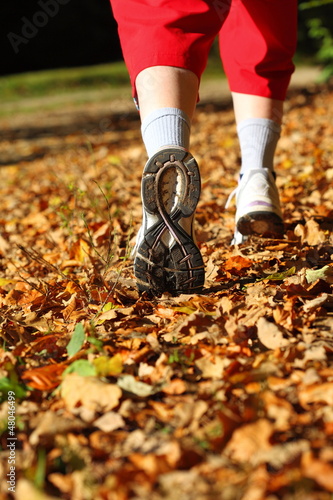 Photo: Woman walking cross country trail in autumn forest Woman walking cross country trail in autumn forest