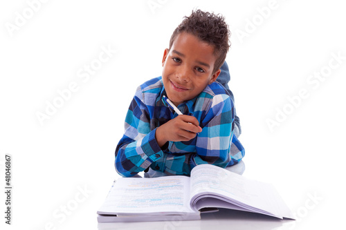 Photo: Little african boy lying down on the floor and reading book Little african boy lying down on the floor and reading book