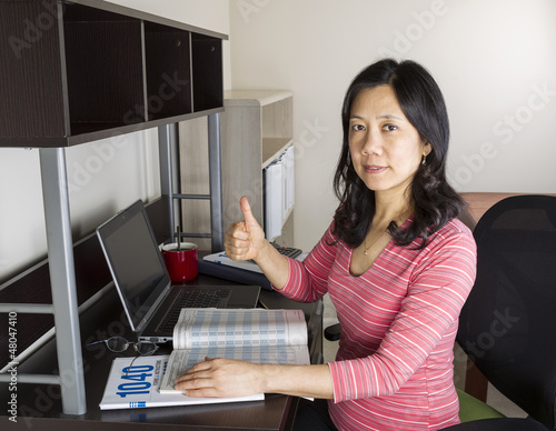 Photo: Positive Mature Asian Doing Personal Income Taxes Positive Mature Asian Doing Personal Income Taxes
