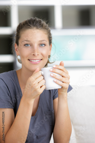 Photo: Close-up of a young woman smiling and drinking coffee Close-up of a young woman smiling and drinking coffee
