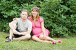 a happy young pregnant woman with her husband resting in a park