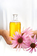 Photo : Hands of young woman holding essential oil and fresh coneflowers Hands of young woman holding essential oil and fresh coneflowers