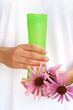 Photo : Hands of young woman holding cosmetics bottle and coneflowers Hands of young woman holding cosmetics bottle and coneflowers