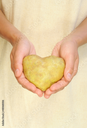 Photo: Hands of young woman holding potato in heart shape Hands of young woman holding potato in heart shape