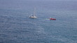 Motorboat towing white yacht to port