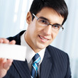 Smiling businessman giving business card, at office