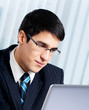 Smiling businessman working with laptop at office