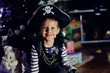 The boy in clothes of the pirate against a New Year tree poses