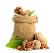 walnuts with green leaves in  burlap bag, isolated on white