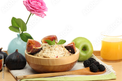 Photo: tasty oatmeal with fruits glass of juice, on wooden table tasty oatmeal with fruits glass of juice, on wooden table