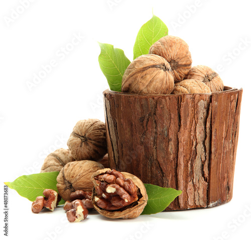 Photo: walnuts with green leaves in woooden vase, isolated on white walnuts with green leaves in woooden vase, isolated on white