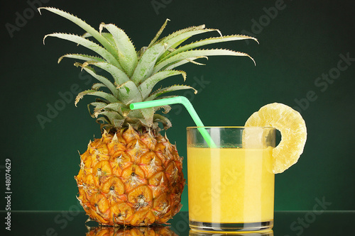 Photo: Ripe pineapple and juice glass on dark green background Ripe pineapple and juice glass on dark green background