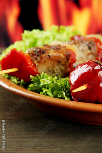 Photo: tasty grilled meat and vegetables on plate, on fire background tasty grilled meat and vegetables on plate, on fire background