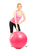 A female athlete posing next to a pilates ball