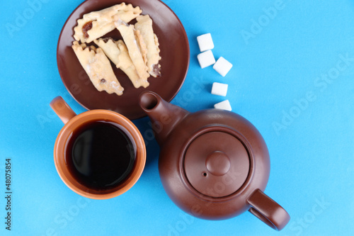 Photo: Top view of cup of tea and teapot on blue tablecloths Top view of cup of tea and teapot on blue tablecloths