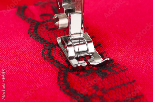 Photo: Closeup of sewing machine working part with red cloth Closeup of sewing machine working part with red cloth