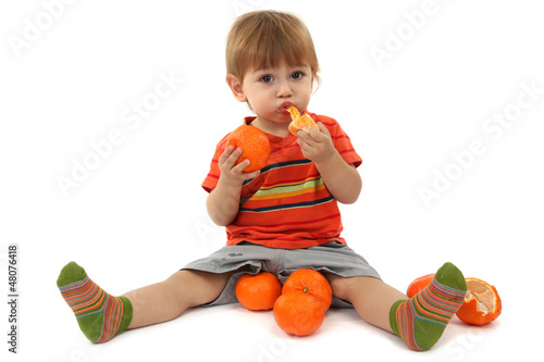 Photo: cute little boy eating tangerines, isolated on white cute little boy eating tangerines, isolated on white