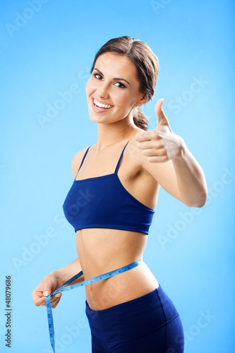Photo: Woman in fitness wear with tape, over blue Woman in fitness wear with tape, over blue