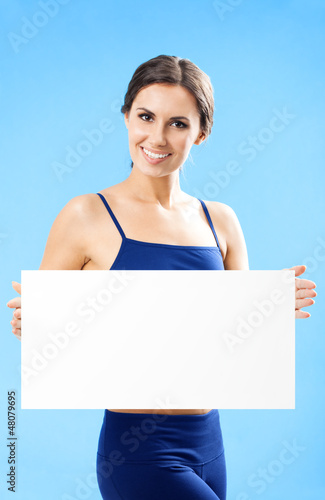 Photo: Woman in fitnesswear showing signboard, over blue Woman in fitnesswear showing signboard, over blue