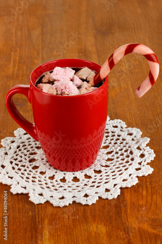 Photo: Cup of coffee with holiday candy on wooden table close-up Cup of coffee with holiday candy on wooden table close-up