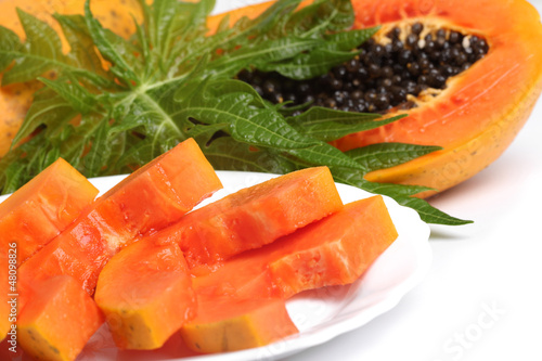 Photo: Ripe papaya and slices with seeds and green leaf isolated on a w Ripe papaya and slices with seeds and green leaf isolated on a w