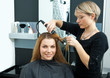 hair stylist curling woman hair in salon