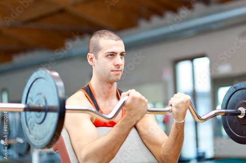 Photo: Young man lifting weights in the gym Young man lifting weights in the gym