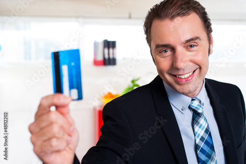 Photo: Handsome male executive holding cash card Handsome male executive holding cash card