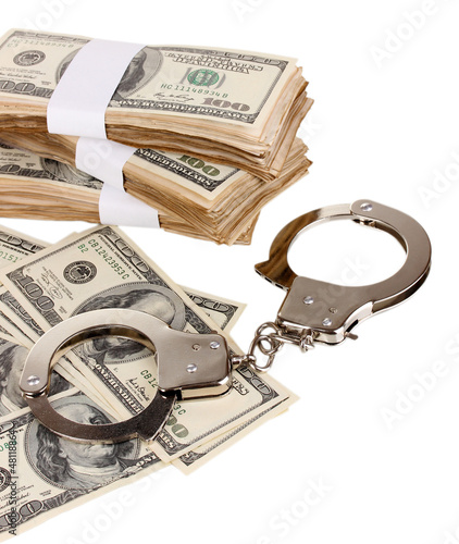 Photo: Handcuffs and packs of dollars on white background close-up Handcuffs and packs of dollars on white background close-up