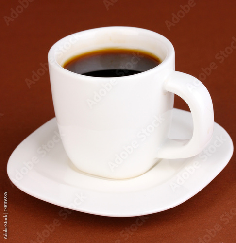Photo: A cup of strong coffee on brown background A cup of strong coffee on brown background