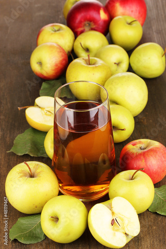 Photo: Useful apple juice with apples around on wooden table Useful apple juice with apples around on wooden table