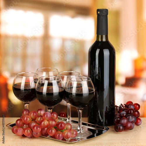 Photo: Red wine in glass and bottle on room background Red wine in glass and bottle on room background