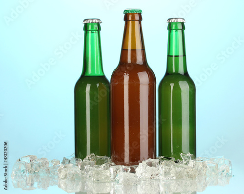 Photo: Beer bottles in ice on blue background Beer bottles in ice on blue background
