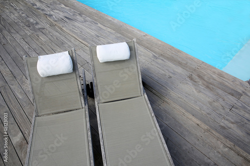 Photo: Closeup of long chairs set by resport pool Closeup of long chairs set by resport pool