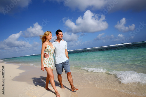 Photo: Young couple walking on a sandy beach Young couple walking on a sandy beach
