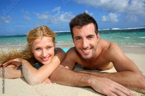 Photo: Cheerful young couple laying on a sandy beach Cheerful young couple laying on a sandy beach