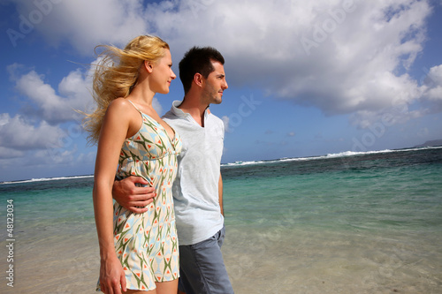 Photo: Young couple walking on a sandy beach Young couple walking on a sandy beach