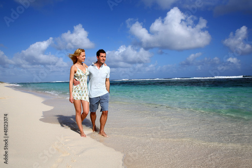 Photo: Young couple walking on a sandy beach Young couple walking on a sandy beach