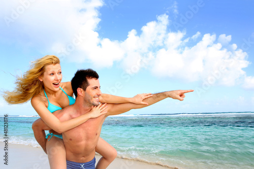 Photo: Man giving piggyback ride to girlfriend at the beach Man giving piggyback ride to girlfriend at the beach
