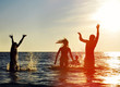 Silhouettes of people jumping in ocean