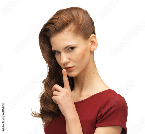 Photo: teenage girl in red dress with finger on lips teenage girl in red dress with finger on lips