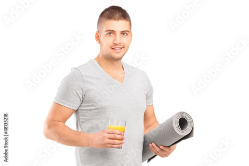 Photo: A male holding a glass of juice and a mat after an excerise A male holding a glass of juice and a mat after an excerise