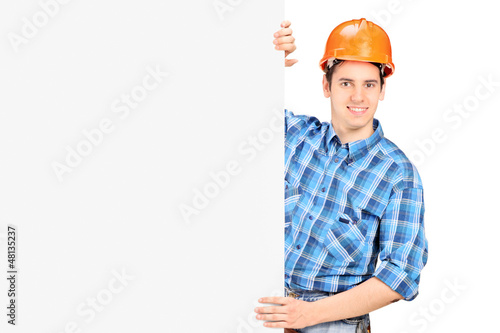 Photo: A male worker with helmet posing behind a panel A male worker with helmet posing behind a panel