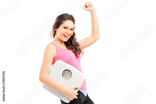 Photo: A young happy female holding a weigh scale A young happy female holding a weigh scale