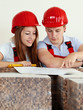 Young worker fixing up a house, discussing in a building lot