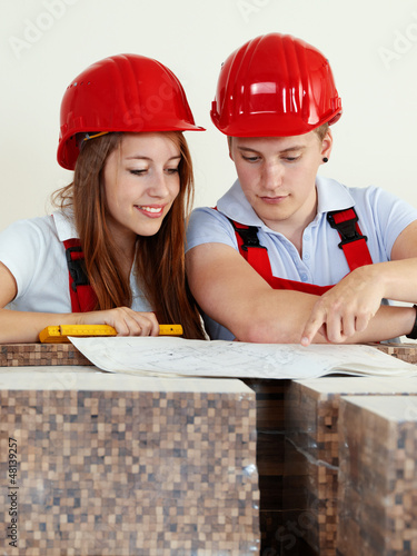 Photo: Young worker fixing up a house, discussing in a building lot Young worker fixing up a house, discussing in a building lot