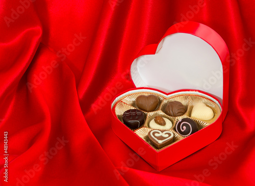 Photo: chocolate pralines in golden box over red silk chocolate pralines in golden box over red silk