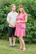 a happy young pregnant woman with her husband rests in a park