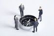 Businessman figurines standing and looking at compass